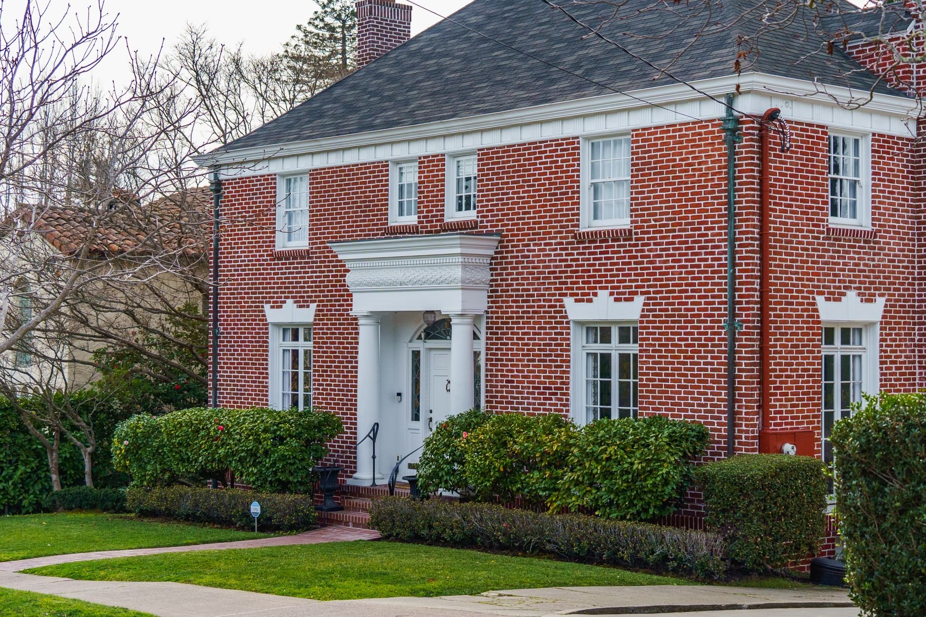 Elegant traditional red brick home with lush garden, showcasing classic American architecture